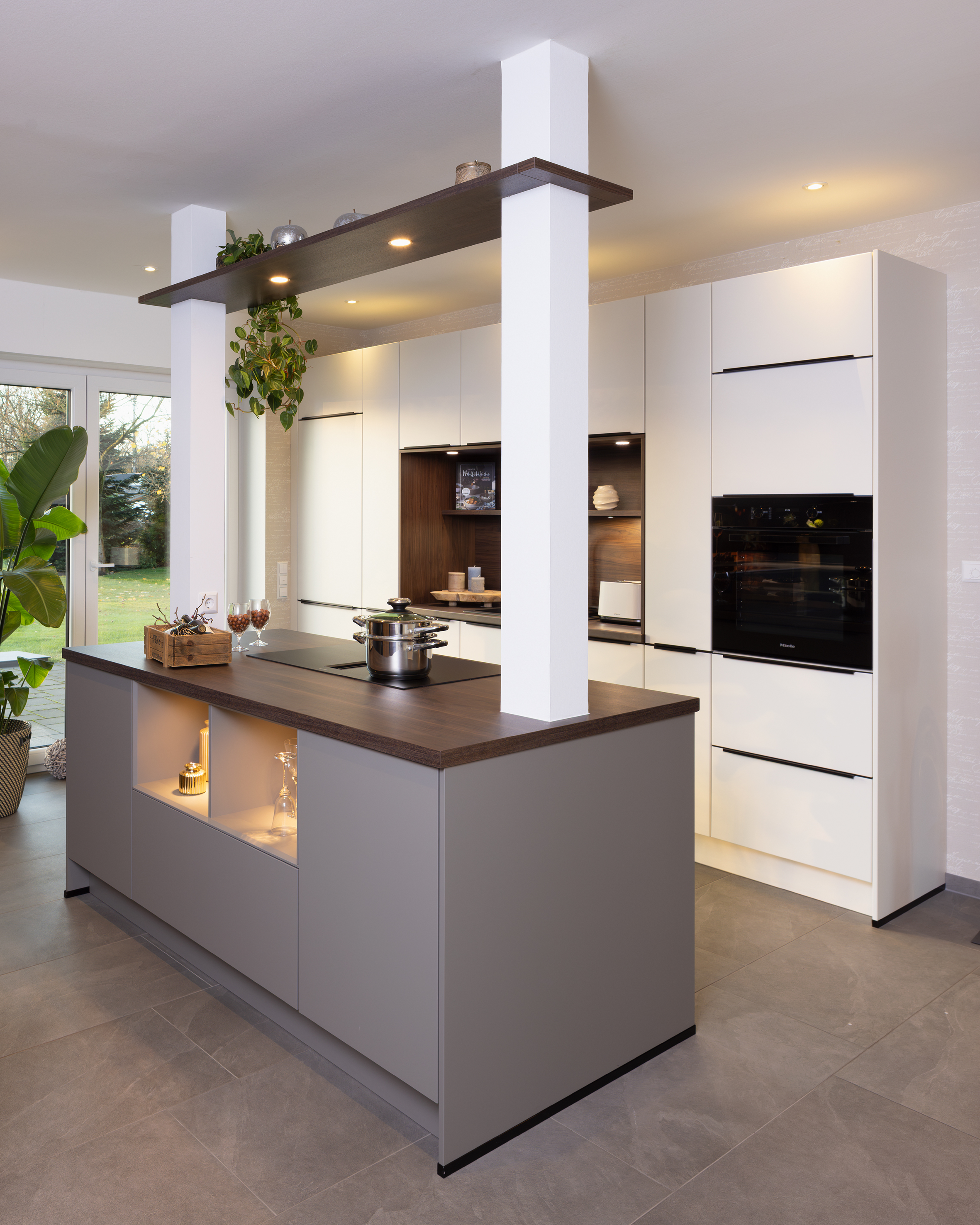 Moderne Küche mit Kochinsel, weißen Schränken und eingebautem Ofen.