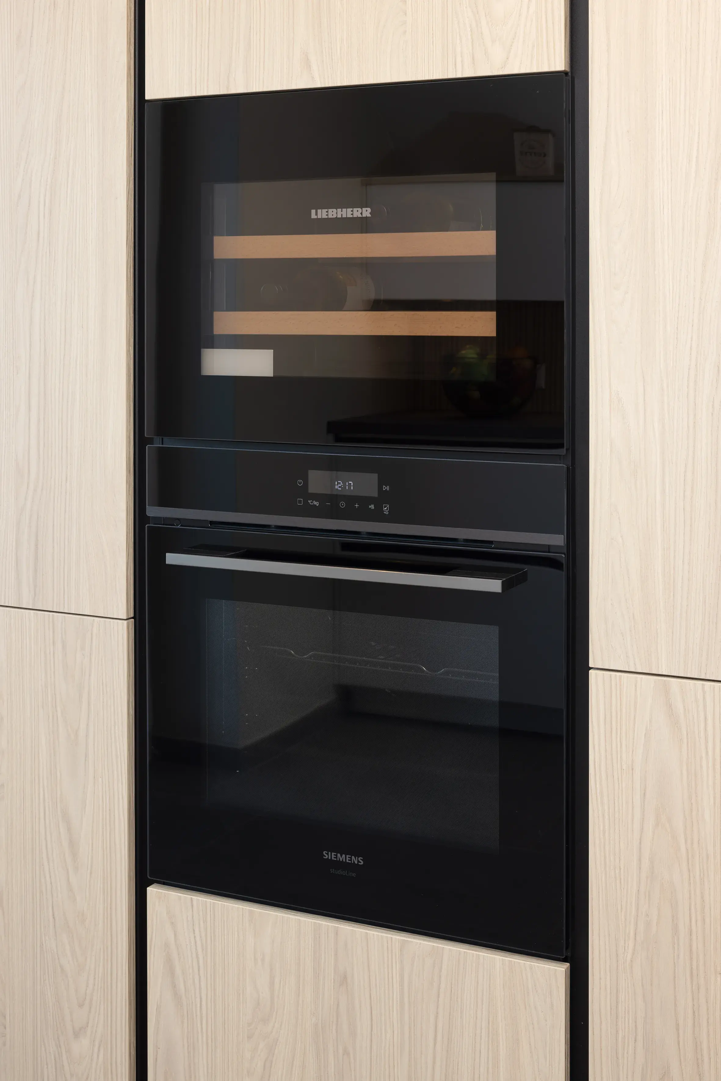 Moderne schwarze Einbauküchengeräte in hellem Holzschrank.