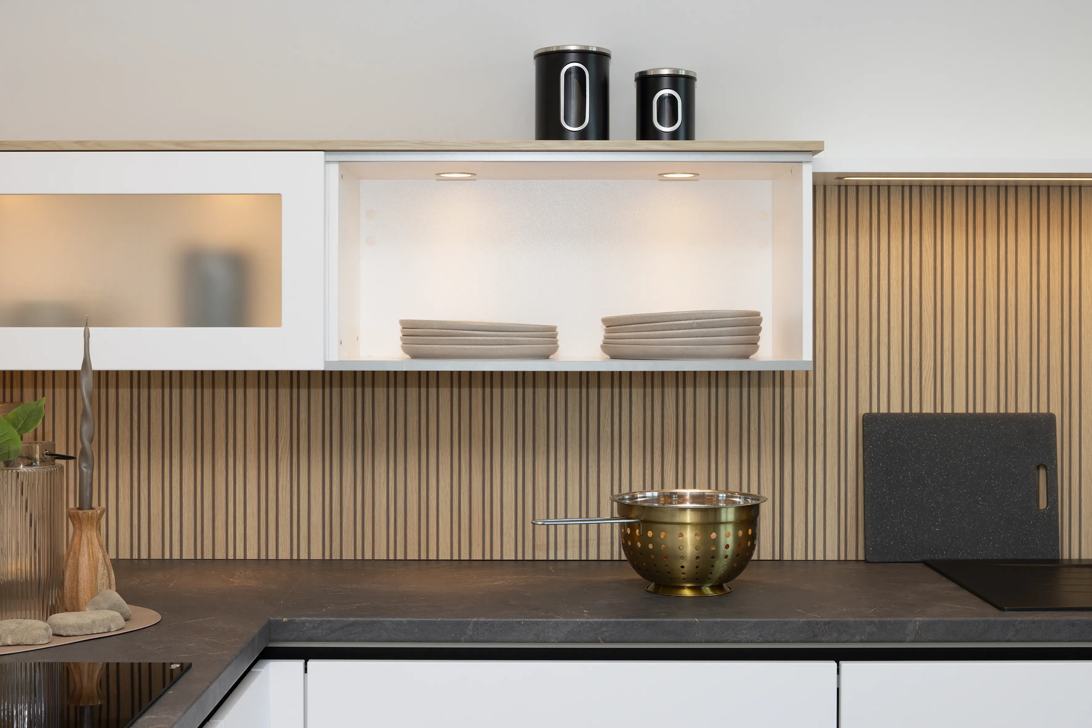 Moderne Küche mit weißen Schränken, Holzakzenten und einer Metallschüssel auf der Arbeitsplatte.