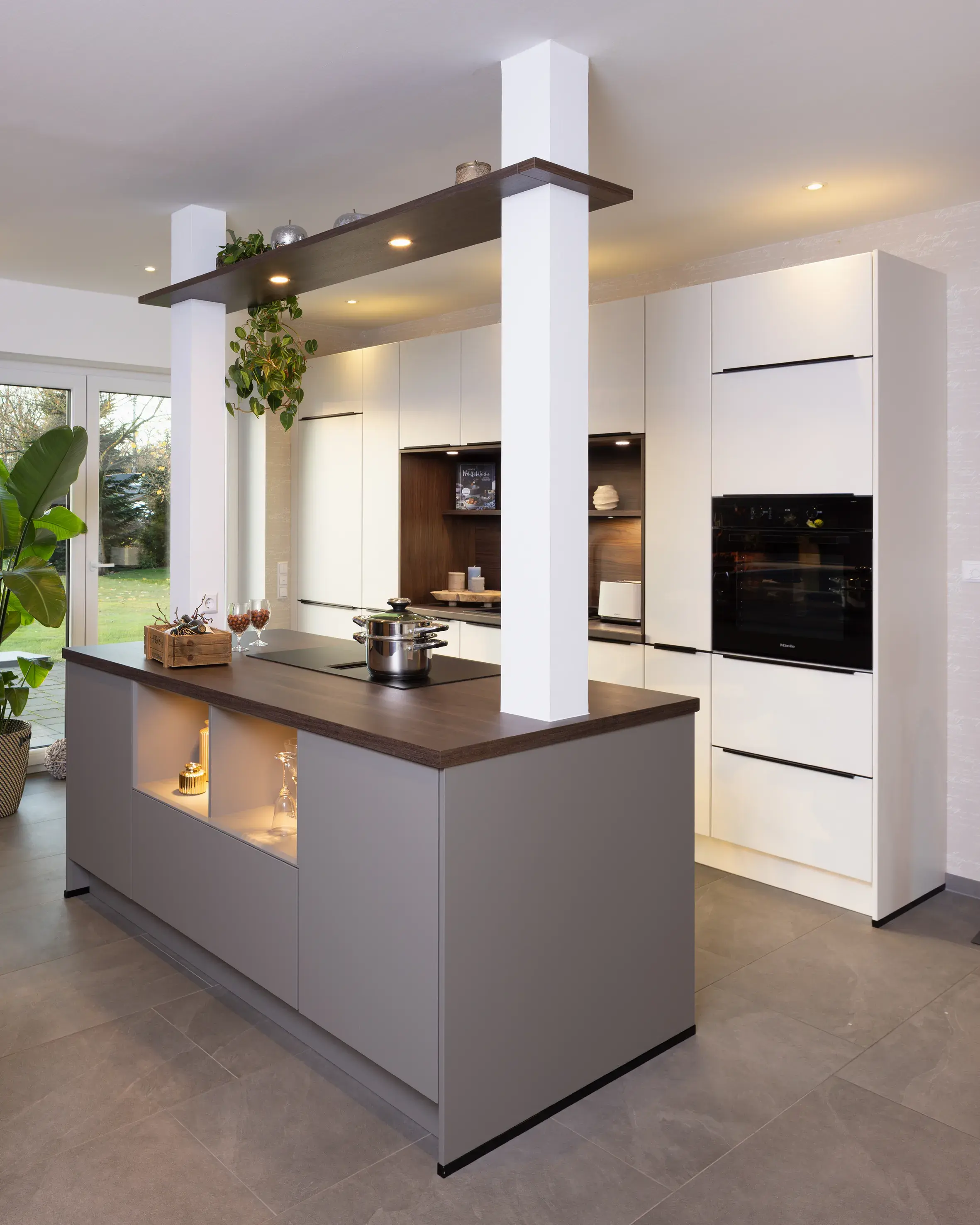 Moderne Küche mit Kochinsel, weißen Schränken und eingebautem Ofen.