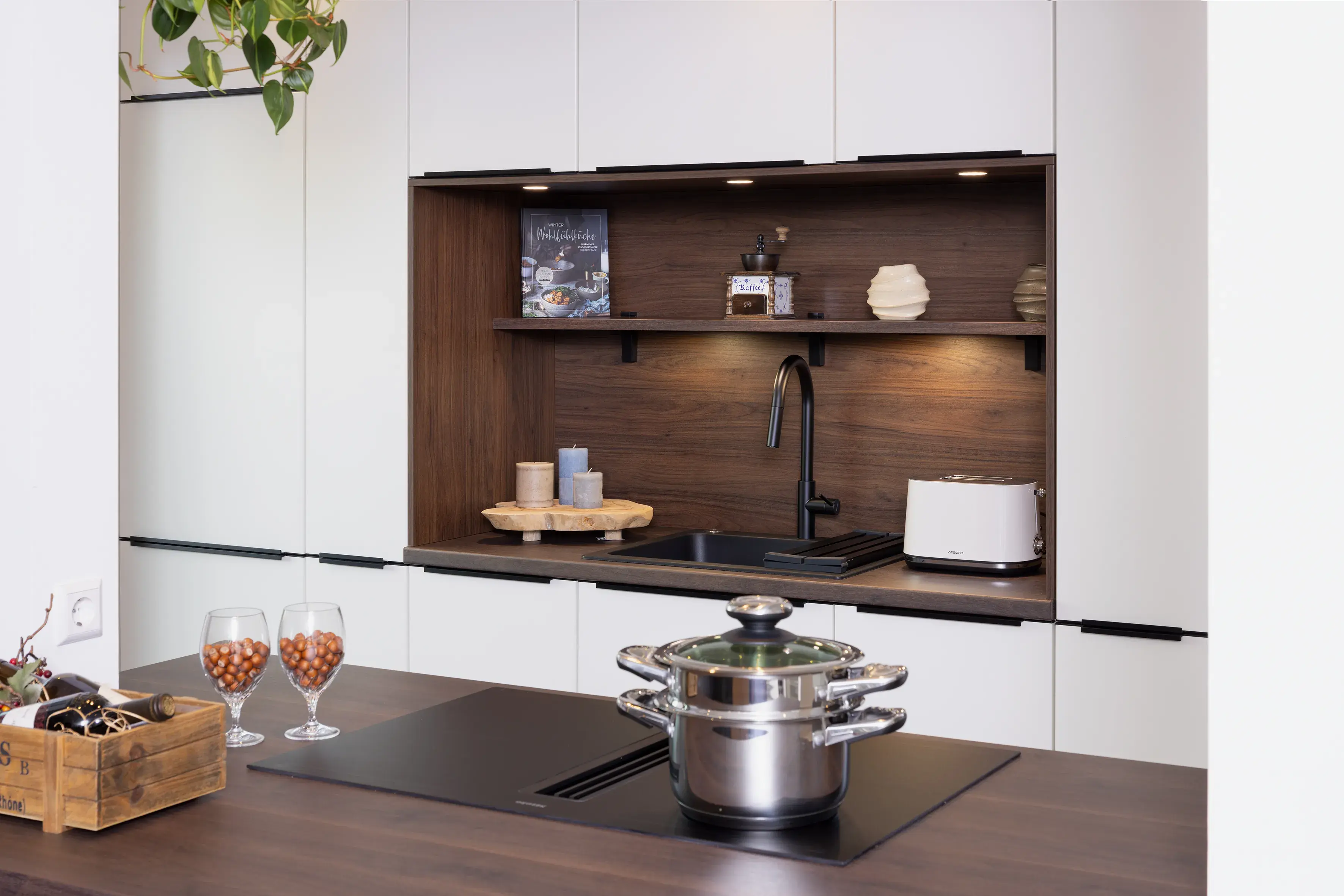 Moderne Küche mit Herd, Topf, zwei Weingläsern und Holzakzenten.