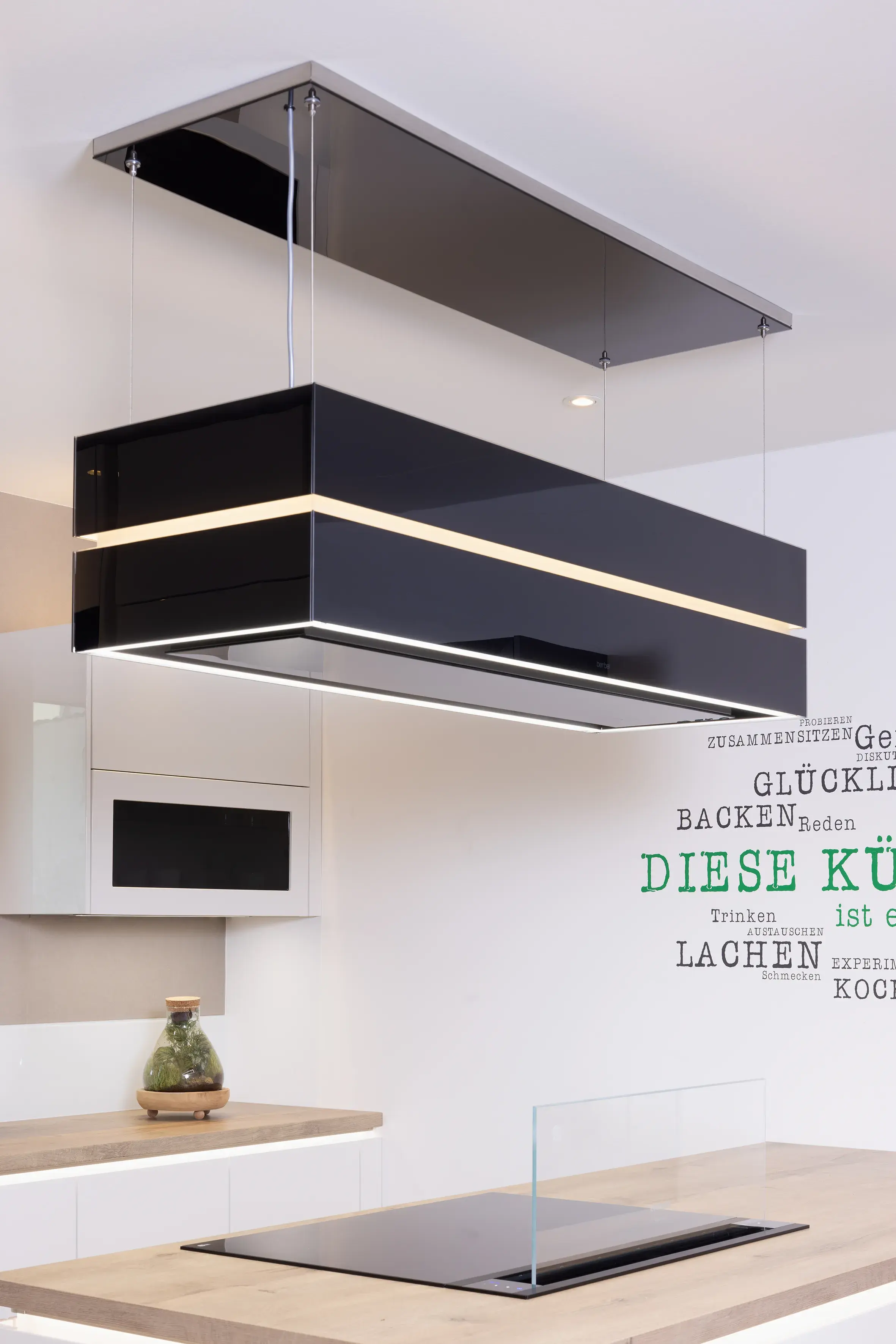 Moderne Küche mit schwarzer Dunstabzugshaube über einem Kochfeld.